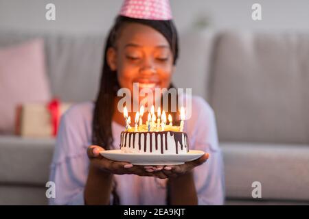 Nahaufnahme der schwarzen Geburtstagsfrau, die Kuchen hält Stockfoto