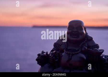 Buddha Figur, bei Sonnenuntergang, auf einer Klippe im Meer Stockfoto