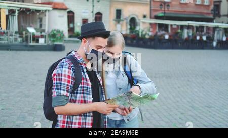 Zwei Touristen in Schutzmasken Überprüfung Karte auf zentralen Stadtplatz, dann bewundern einige schöne Stelle. Reisen während der Pandemie. Stockfoto