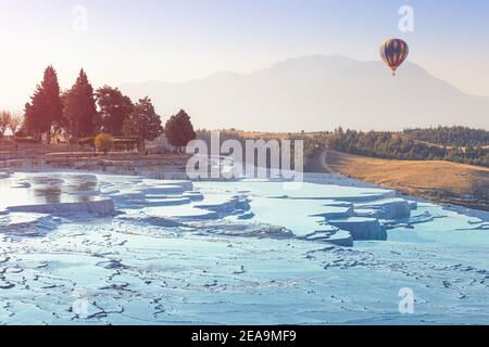Heißluftballon mit Touristen fliegen über die berühmte türkische Touristenattraktion - Pamukkale Resort mit Thermalquellen und Kalkstein Travertinen Stockfoto