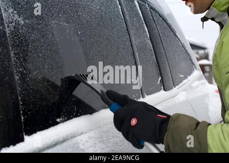 Winterszene, menschliche Hand im Handschuh kratzen Eis aus dem Auto Stockfoto