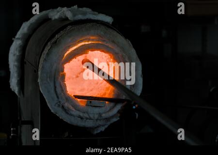 Glasofen erhitzen eine punty ruht auf einem Joch in Hotshop bereit, geschmolzenes Glas zu sammeln und in funktionale Glaskunst geblasen werden. Stockfoto