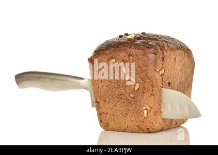 Ein ganzes frisch duftendes Roggenbrot mit Sonnenblumenkernen und einem Metallmesser. Der Hintergrund ist weiß. Stockfoto