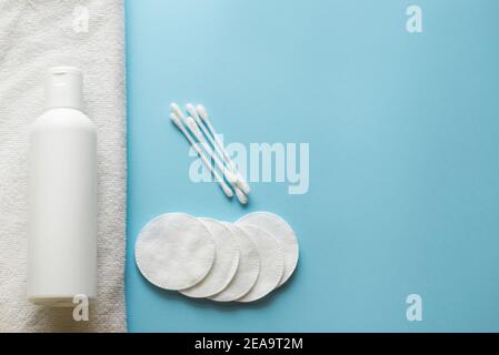 Wattestäbchen für Ohren und Pads für Gesicht auf blauem Hintergrund und Lotion auf weißem Hintergrund. Speicherplatz kopieren Stockfoto