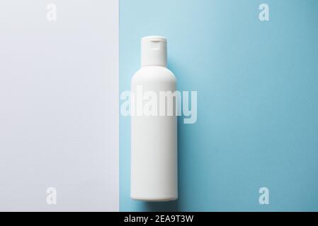 Weiße Shampoo-Flasche auf einem blauen und weißen Hintergrund. Speicherplatz kopieren Stockfoto