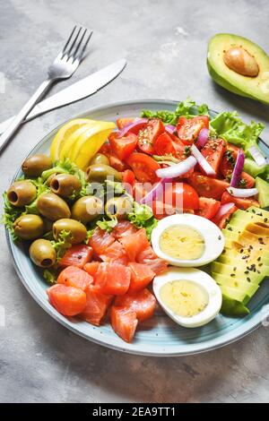 Ketogene, paleo Diät-Schüssel mit gesalzenem Lachs Fisch, Zitrone, Avocado, Oliven, gekochtem Ei, Tomaten, grünem Salat, gesunde Ernährung Trend Stockfoto