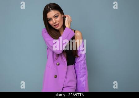 Foto von positiven jungen Unternehmen lange Haare Brünette Frau tragen lila Anzug isoliert auf blauem Hintergrund. Speicherplatz kopieren Stockfoto