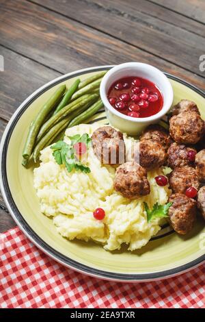 Schwedische Fleischbällchen mit Kartoffelpüree und grünen Bohnen auf Holzgrund. Stockfoto