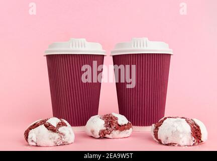 Zwei Pappbecher Kaffee und Kekse auf rosa Hintergrund Stockfoto