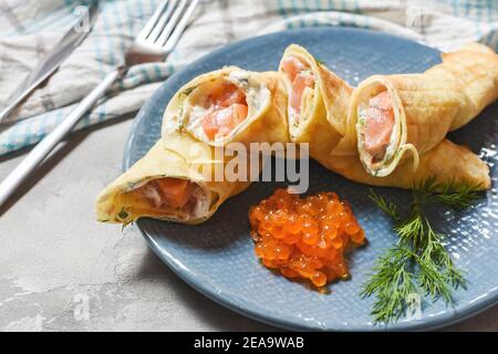 Leckeres Frühstück - Crepes mit geräuchertem Lachs, saurer Sahne und Caviarch auf Betongrund. Stockfoto