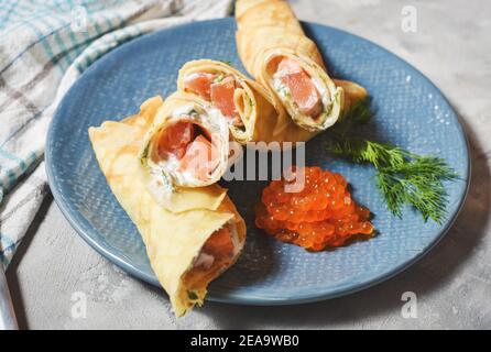 Leckeres Frühstück - Crepes mit geräuchertem Lachs, saurer Sahne und Caviarch auf Betongrund. Stockfoto