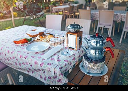 Reichhaltiges und leckeres türkisches Frühstück mit Käse und Vorspeisen, frischem Gemüse und einer authentischen Doppel-Teekanne zum Brühen und kochendem Wasser. Stockfoto