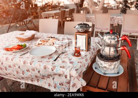 Reichhaltiges und leckeres türkisches Frühstück mit Käse und Vorspeisen, frischem Gemüse und einer authentischen Doppel-Teekanne zum Brühen und kochendem Wasser. Stockfoto