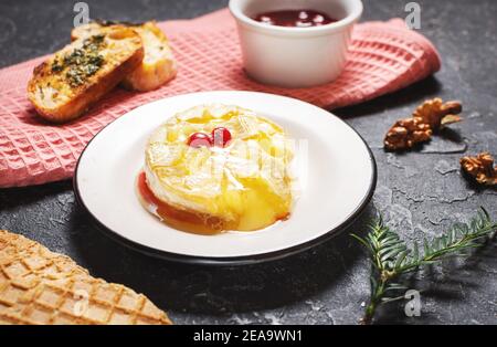 Lecker schön gebackenen Camembert mit Honig, Walnüssen, Kräutern und Preiselbeeren Stockfoto
