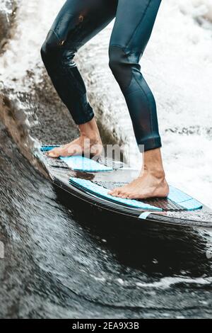 Unkenntlich fit kaukasischen Mann reitet wecken Brandung auf Fluss oder See am Abend in der untergehenden Sonne. Konzept für Wassersport, Wochenendaktivitäten. Vorderansicht. Stockfoto