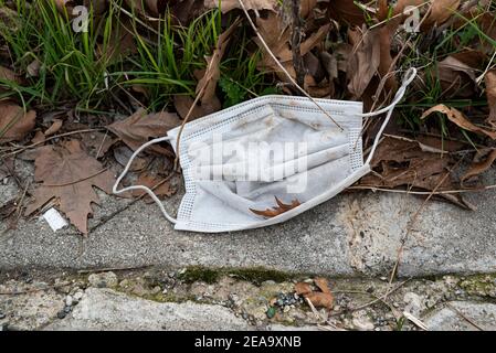 Maske für den medizinischen Schutz verloren auf dem Boden. Einwegmaske liegt auf der Straße. Falsche Entsorgung der Gesichtsmaske. Stockfoto