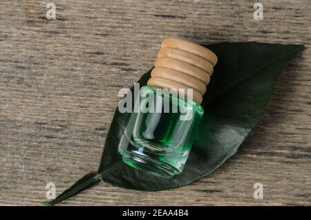 Zitronengeschmack von smaragdgrüner Farbe in einer Glasflasche mit einem Holzstopfen auf einem grünen Blatt. Die dunkle Taste. Stockfoto