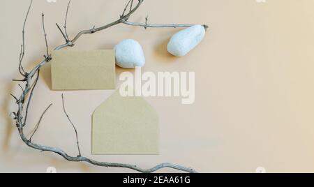 Branding-Mockup-Schablone mit Umschlag blank, weißen Steinen und trockenem Baumbrunch als Naturelemente auf neutralem beigen Hintergrund. Bannerfoto mit Kopie Stockfoto
