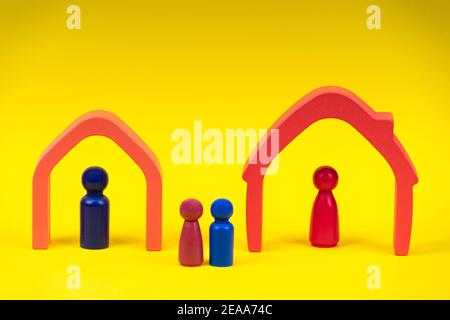 Holzfiguren, Miniaturparaturen, die in Häusern stehen und Kinder dazwischen auf gelbem Hintergrund Stockfoto