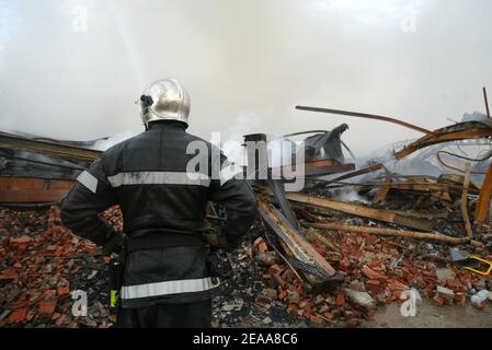 Feuerwehrleute bei der Arbeit in den Ruinen eines chinesischen Textillagers, das am 12th. November 2005 in der Nacht 5 in der Pariser Vorstadt Le Bourget, Frankreich, in Brand gesetzt wurde. Kleine, mobile Gruppen von Jugendlichen haben hunderte weitere Autos angefackelt und die Gewalt und Brandanschläge, die die Vororte der Hauptstadt eine Woche lang erschüttert haben, haben sich auf andere französische Städte ausgebreitet. Foto von Mehdi Taamallah/ABACAPRESS.COM Stockfoto