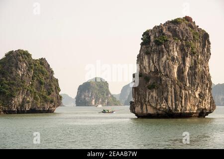 Fischerboot zwischen Felsen, Halong Bay, Vietnam Stockfoto