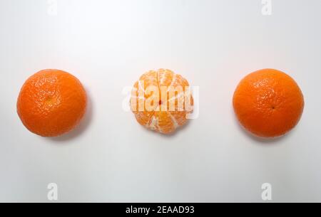 Drei Mandarinen mit einer Mitte, die auf weißem Hintergrund abgeschält ist Mit Schatten Stockfoto