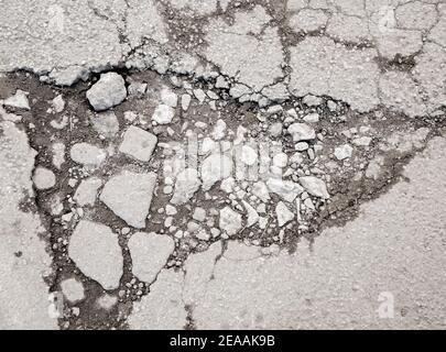 Großes Schlagloch mit Steinen auf der Asphaltstraße Stockfoto