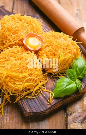 Tagliatelle Pasta ist dünn. Traditionelle italienische Namen Angel Hair. Italienische Eiernudeln, hausgemacht und frisch auf einem Holztisch. Rustikale Küche des Nordens von Italien. Vertikales Foto Stockfoto