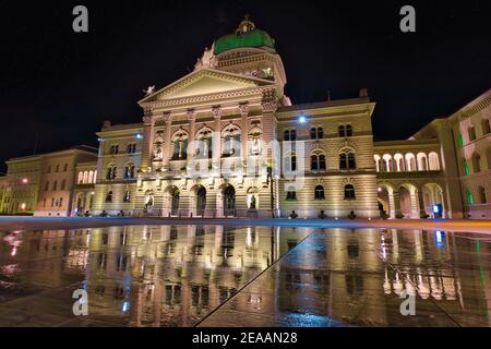 Bundespalastfassade in Bern, Schweiz bei Nacht beleuchtet. Schweizer Parlamentsgebäude, das sich im Wasser des Bundesplatzn spiegelt. Wahrzeichen von Stockfoto