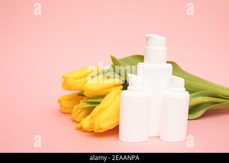 Gelbe Tulpen auf rosa Hintergrund mit Kosmetikflaschen Behälter. Modell. Happy Mothers Day, Frauen Tag Glückwünsche Konzept, Geschenk, koreanisch Stockfoto