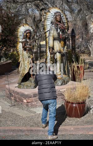 Ein Tourist fotografiert Bronzeskulpturen des indianischen Häuptlings Red Cloud vor einer Kunstgalerie in Santa Fe, New Mexico. Stockfoto