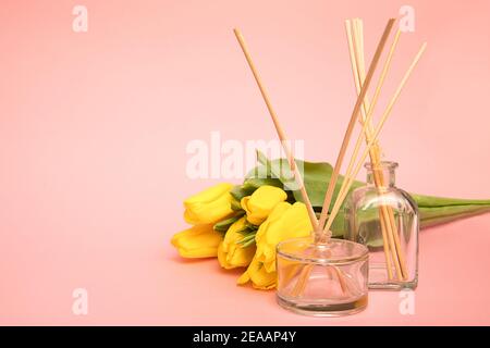 Lufterfrischer mit hölzernen Duftstäbchen und Tulpenblüten auf rosa Hintergrund mit Kopierraum. Konzept der frischen Luft zu Hause Stockfoto