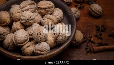 Nüsse. Ganze Walnüsse in einer Steingutschale auf einem dunklen Holztisch. Stockfoto