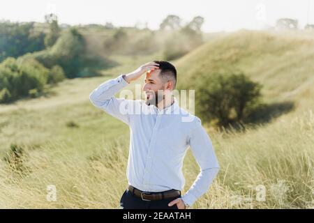 Schöner bärtiger araber in Sonnenbrille auf dem grünen Hügel Hintergrund. Selbstbewusster muslimischer Geschäftsmann. Arabischer Mann in weißem Hemd getragen Stockfoto