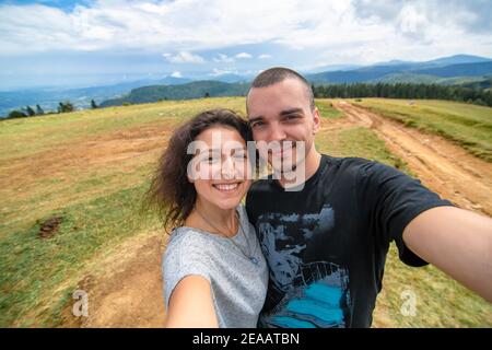 Junges Paar Umarmungen und Selfie mit erstaunlichen Berglandschaft Hintergrund. Stockfoto