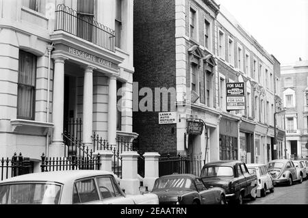 Großbritannien, West London, Notting Hill, 1973. Heruntergekommene und heruntergekommene, große, vierstöckige Häuser werden langsam restauriert und neu dekoriert. Nr. 14-16 Powis Terrasse, Hedgegate Court, mit einem Seiteneingang zum Talbot Tabernakel. Freihaltung Investition für Verkauf Zeichen. Stockfoto