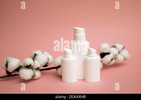 Weißer Behälter für kosmetische Plastikflasche mit Baumwollblume, blanko Etikett für Mock up Branding, Naturschönheits-Produktkonzept. Rosa Hintergrund Stockfoto
