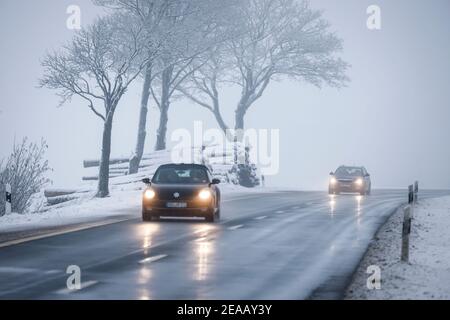 12/07/2020, Winterberg, Sauerland, Nordrhein-Westfalen, Deutschland, Autos fahren auf einer Landstraße durch eine verschneite Landschaft. 00X201207D067CARO Stockfoto