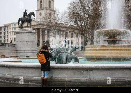 London, Großbritannien. Februar 2021, 08. UK Wetter: Eine Frau macht ein Foto von einer eisbedeckten Statue in einem Brunnen am Trafalgar Square. Quelle: Waldemar Sikora Stockfoto