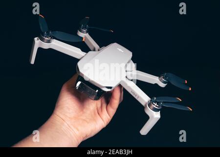 Kiew, Ukraine - 02. Februar 2021: DJI Mavic Mini 2 Drohne Nahaufnahme. Hand hält ausgeklappten Quadcopter auf schwarzem Hintergrund Stockfoto