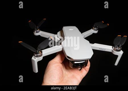 Kiew, Ukraine - 02. Februar 2021: DJI Mavic Mini 2 Drohne Nahaufnahme. Hand hält ausgeklappten Quadcopter auf schwarzem Hintergrund Stockfoto