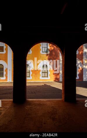 Blick durch steinerne Torbögen in einen Innenhof mit alten Gebäuden. Stockfoto