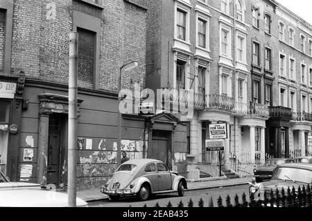 Großbritannien, West London, Notting Hill, 1973. Heruntergekommene und heruntergekommene, große, vierstöckige Häuser werden langsam restauriert und neu dekoriert. Ledbury Road (Talbot Road auf der linken Seite). No. 129 Eigentumshaus zu verkaufen. Stockfoto