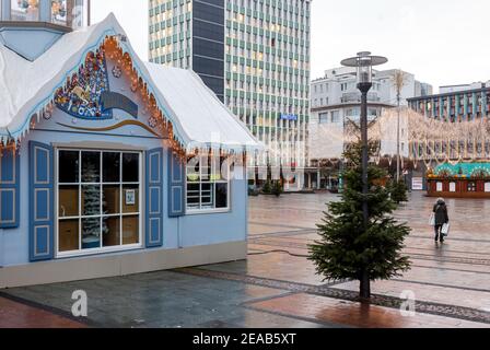 Essen, Ruhrgebiet, Nordrhein-Westfalen, Deutschland - Essener Innenstadt in Zeiten der Koronakrise mit der zweiten Sperre am Vorabend von Weihnachten sind die Geschäfte und die wenigen Weihnachtsmarktstände geschlossen, eine Seniorin geht mit ihren Einkäufen über den leeren Kennedyplatz. Stockfoto