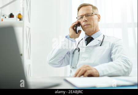 Schöner männlicher Arzt mit Telefongespräch in der Klinik Stockfoto