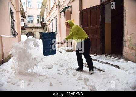 Lviv, Ukraine. Februar 2021, 08th. Eine Frau mit einer Schaufel in den Händen räumt Schnee auf dem Hof eines der Häuser in Lemberg. In den letzten 24hrs sind mehr als 30cm Schnee in Lviv gefallen. Aufgrund der Tatsache, dass die öffentlichen Versorgungsunternehmen es nicht schaffen, Schnee zu entfernen, nahmen Einwohner von Lemberg auf die Straßen, um Schnee von schweren Schneefällen angehäuft zu reinigen. Kredit: SOPA Images Limited/Alamy Live Nachrichten Stockfoto