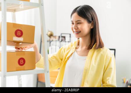 Startup Kleinunternehmen, junge asiatische Frau Check-und Verpackung von Boxen für Produkte an Kunden zu senden. Arbeiten im Home Office. Stockfoto