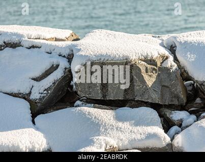 Große Felsbrocken, die vom Wasser mit Schnee bedeckt sind Stockfoto