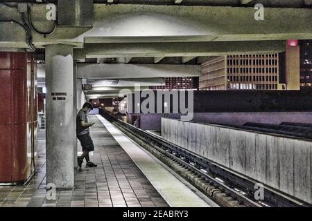 Ein junger Mann wartet auf den Zug auf dem Government Center Metrorail Plattform spät in der Nacht in der Innenstadt von Miami, Florida. Stockfoto