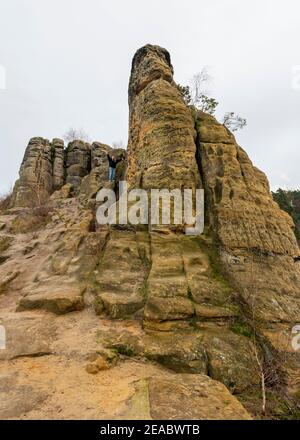 Deutschland, Sachsen-Anhalt, Halberstadt, Frau steht auf einem Sandsteinfelsen in der Klusberge, Bergkette im Vorharz. Stockfoto